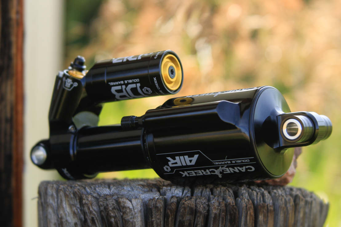 Two black shock absorbers on a wooden post with a blurred natural background