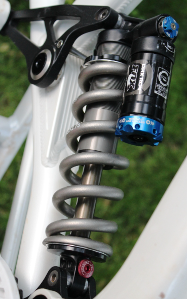 Close-up of a bicycle suspension fork with Fox branding on a blurred grass background