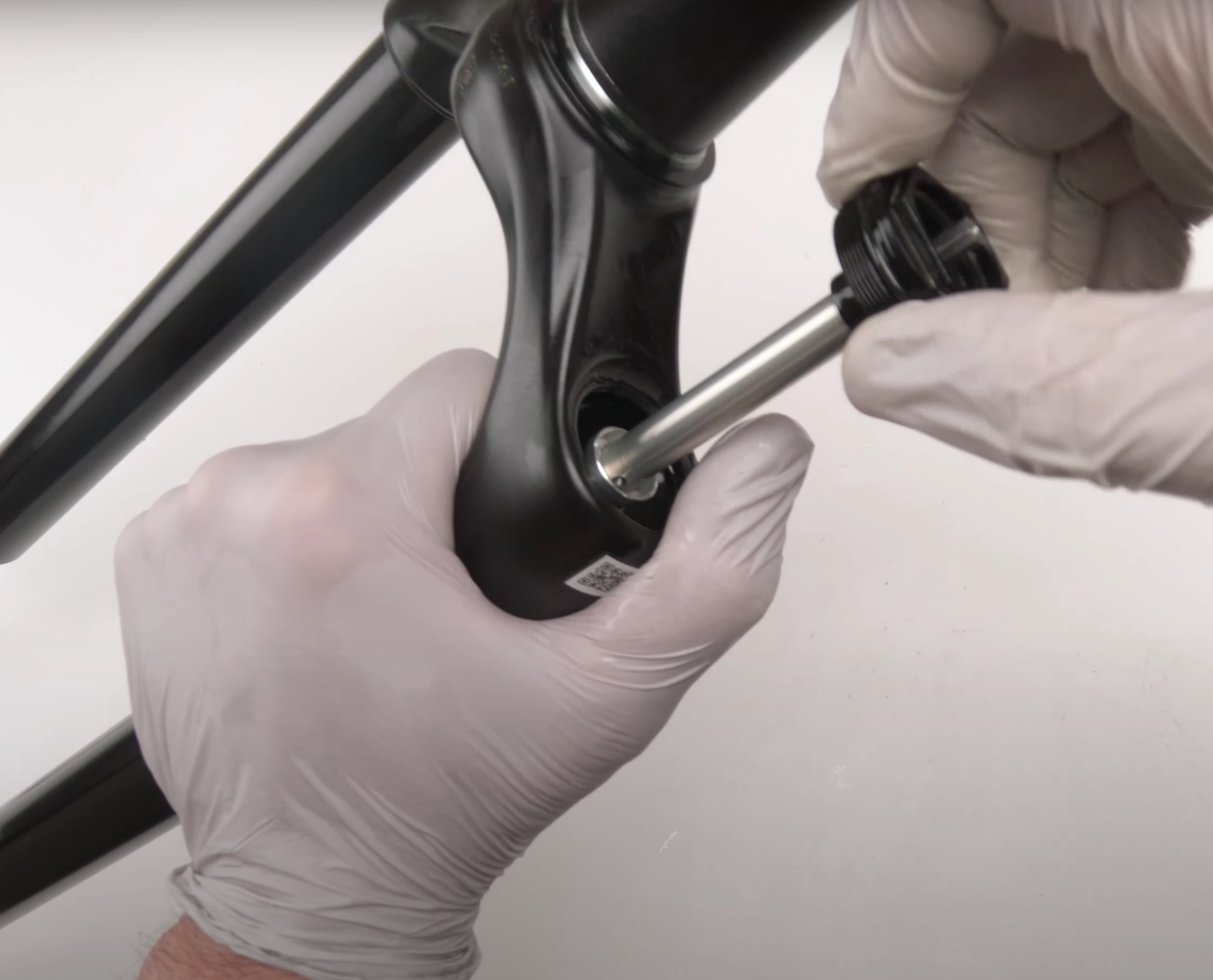 Person wearing gloves using a tool on a bicycle suspension mtb