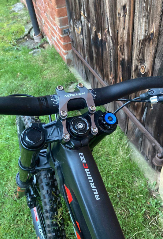 Close-up of a bicycle handlebar with 'Nordon' brand name, against a wooden fence and grass background.