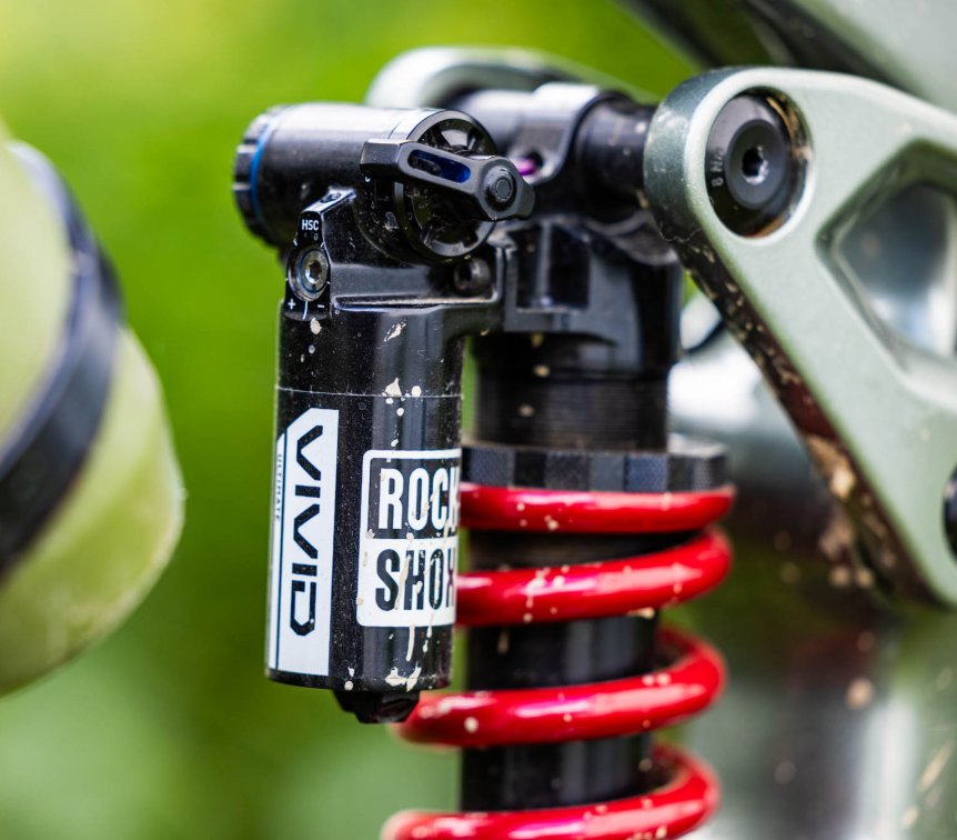 Close-up of a Rock Shox suspension fork on a bicycle with a blurred green background